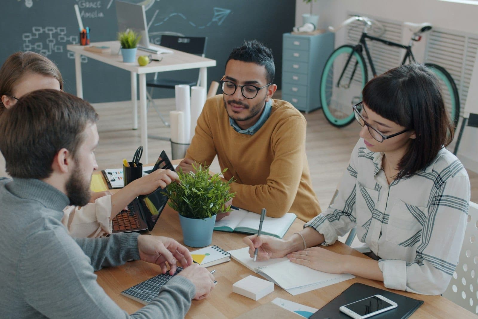 A team working around a table covered in laptops and notes